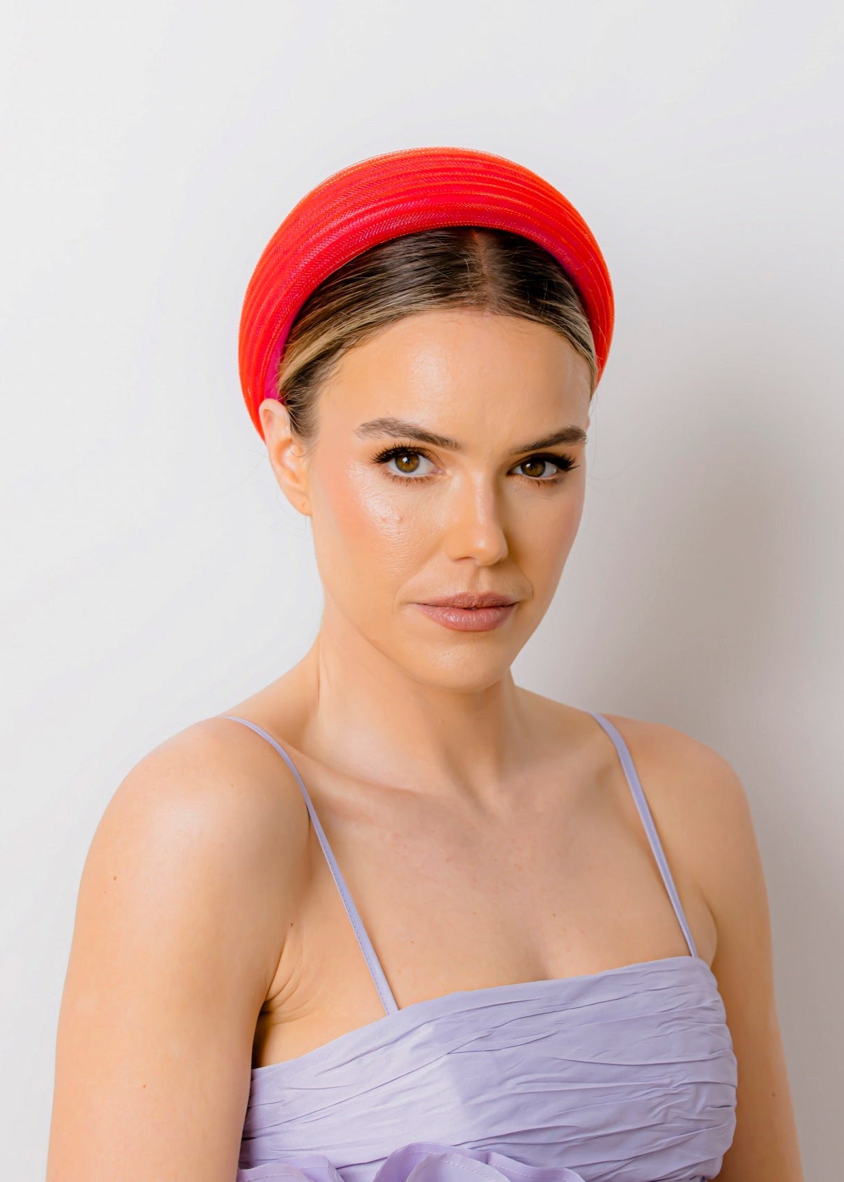 Woman wearing a purple dress and a red headband against a white background