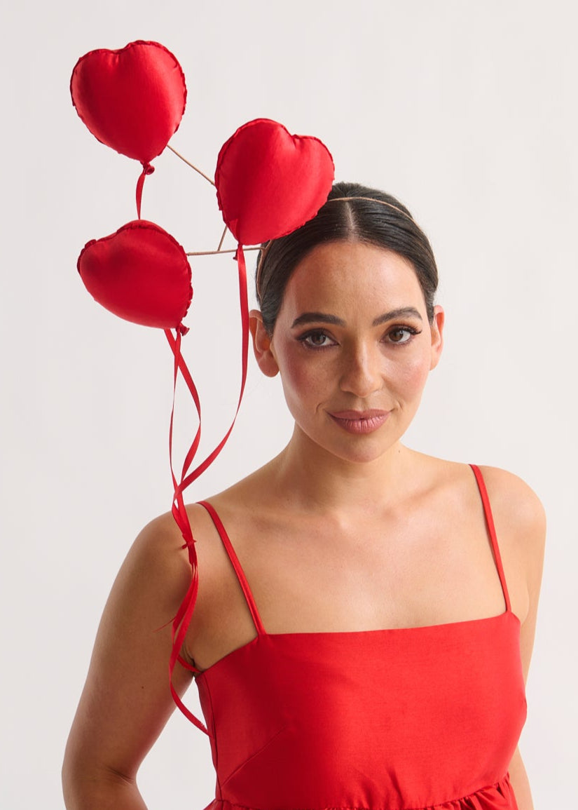 Woman in a red dress with heart-shaped headpiece on a white background