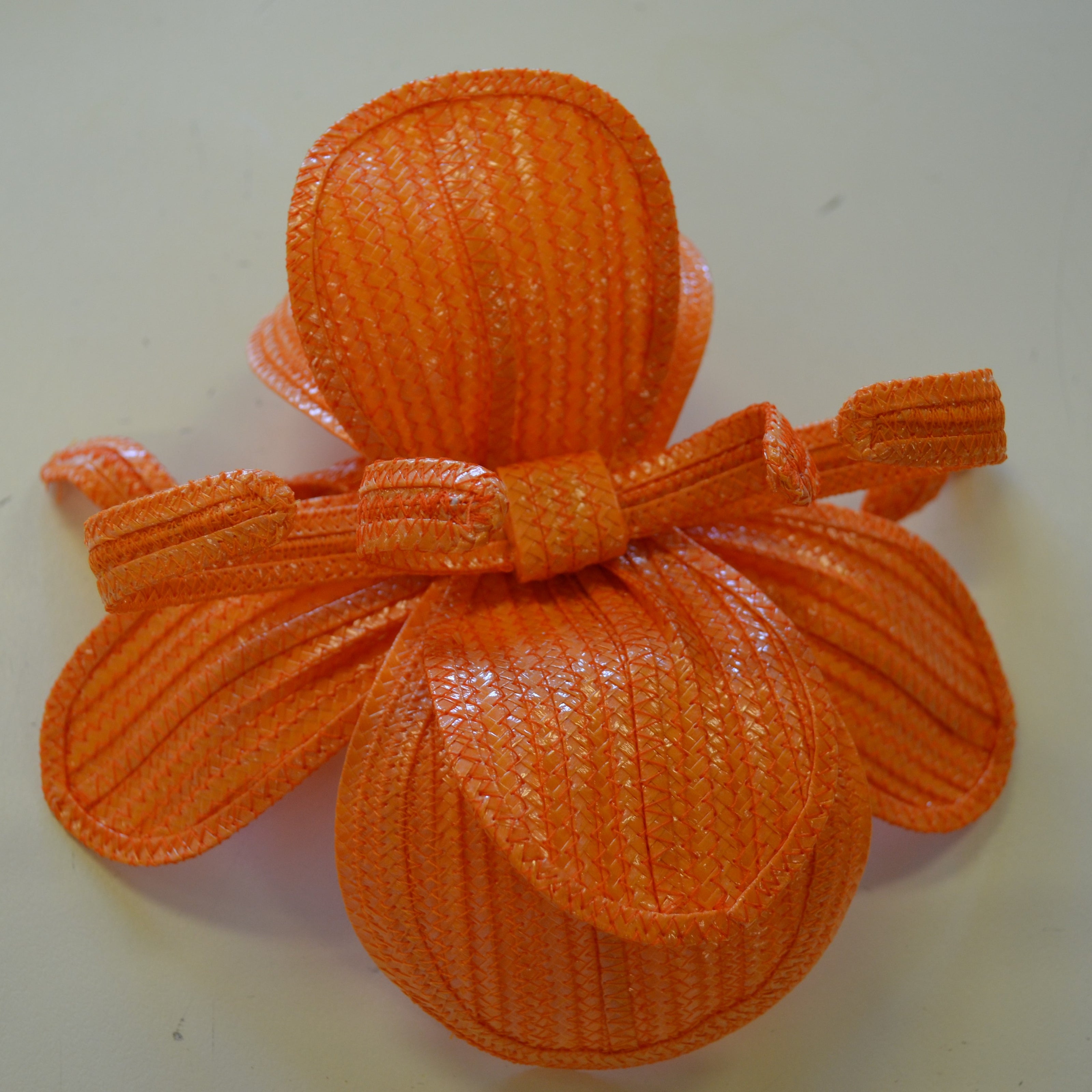 orange swiss braid trims hat on a white bench
