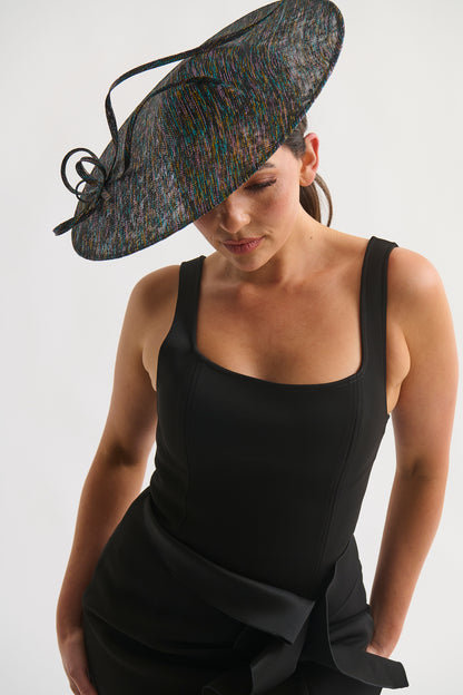 Woman wearing a large decorative hat and a black dress on a white background