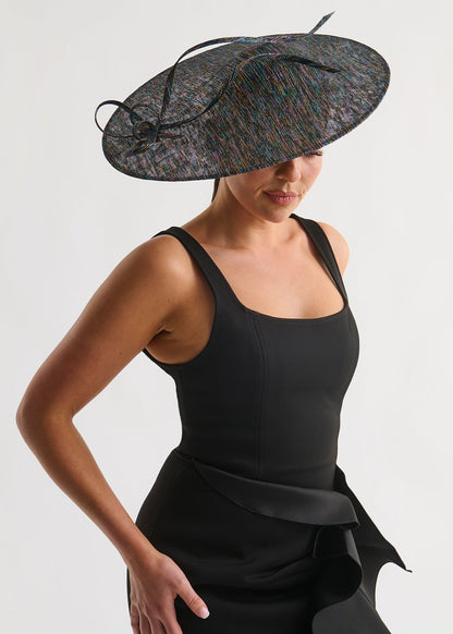 Woman wearing a black dress and decorative hat on a white background