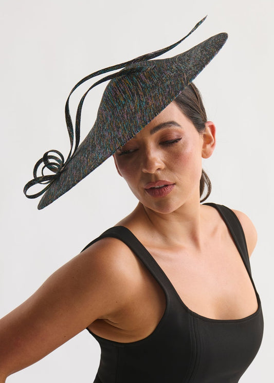 Woman wearing a black dress and decorative hat against a white background
