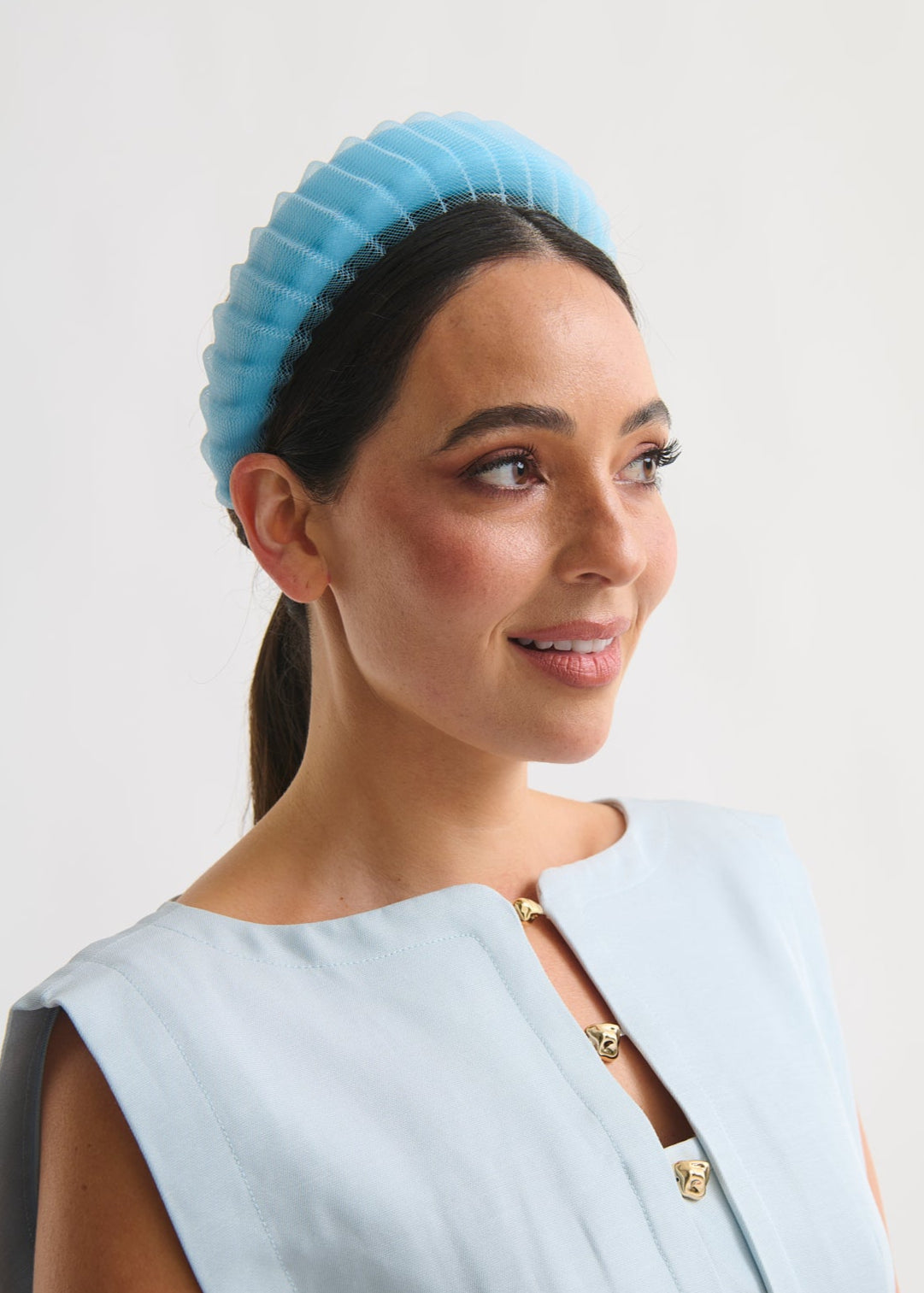 Woman wearing a light blue headband and dress against a white background