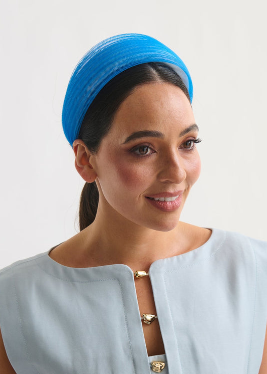 Woman wearing a blue headband against a white background