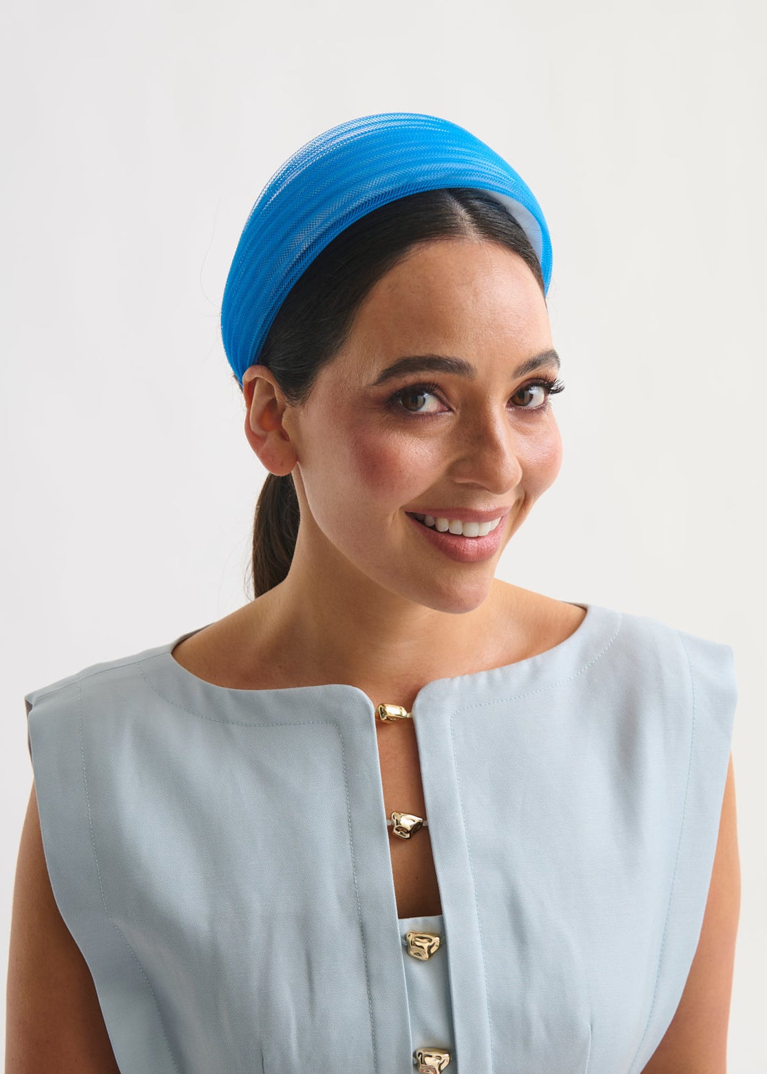 Woman wearing a blue headband against a white background