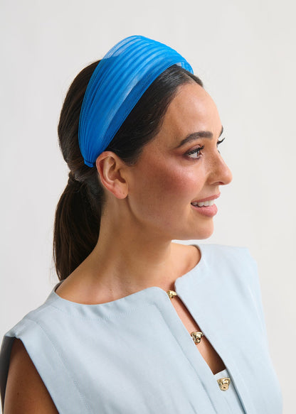 Woman wearing a blue headband against a plain background
