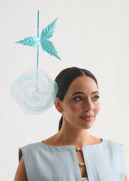 Woman wearing a light blue sleeveless top with gold buttons, standing against a white background.