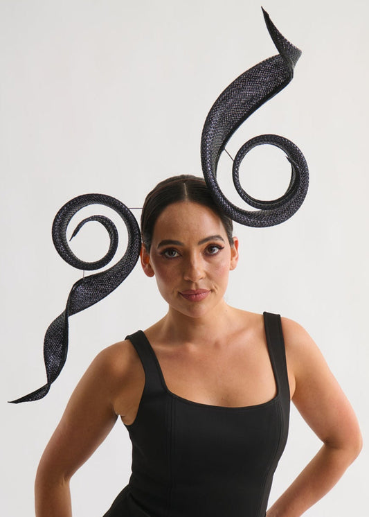 Woman wearing a black dress with a large decorative headpiece on a white background