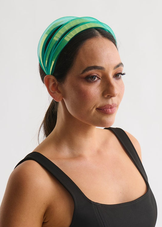 Woman wearing a black sleeveless dress and green headband on a white background