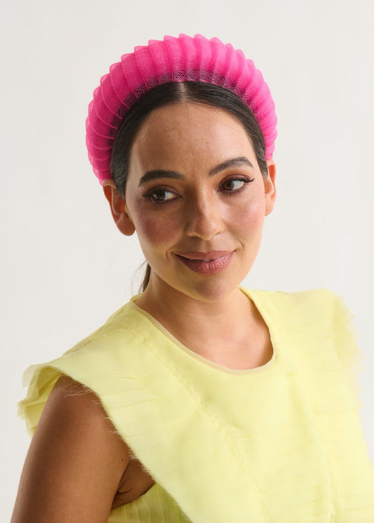 Woman wearing a bright yellow dress and pink headband against a white background