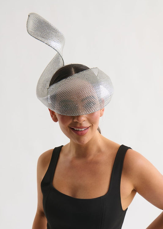 Woman wearing a silver swirl headpiece and a black dress against a white background