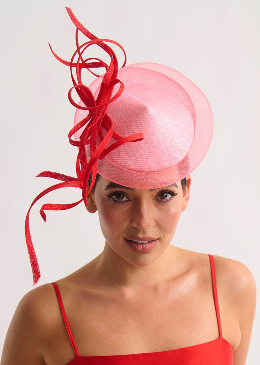 Woman wearing a pink hat with red decorative elements against a white background