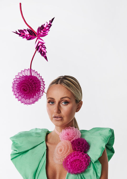 Woman wearing a green dress with floral embellishments against a white background