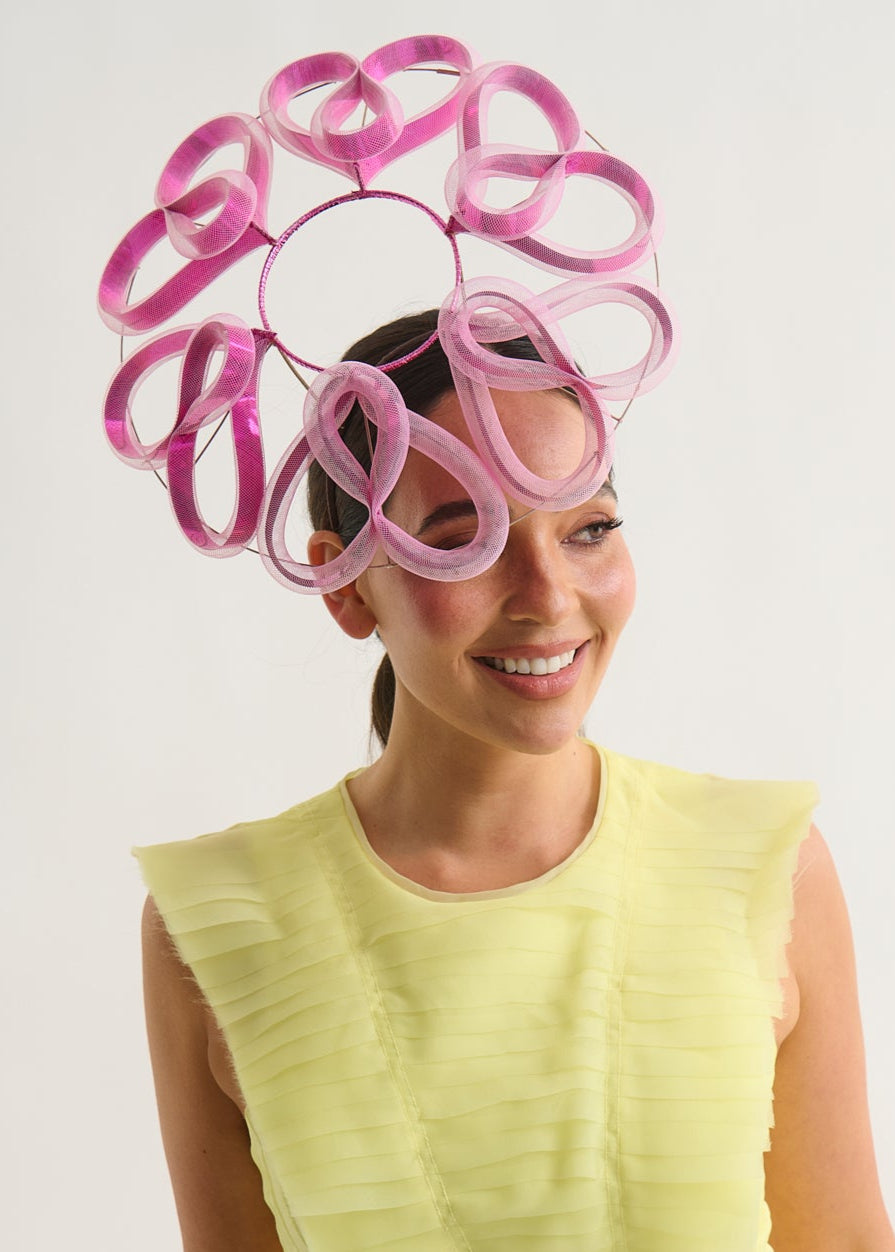 Woman wearing a bright yellow dress and a decorative magenta headpiece against a white background