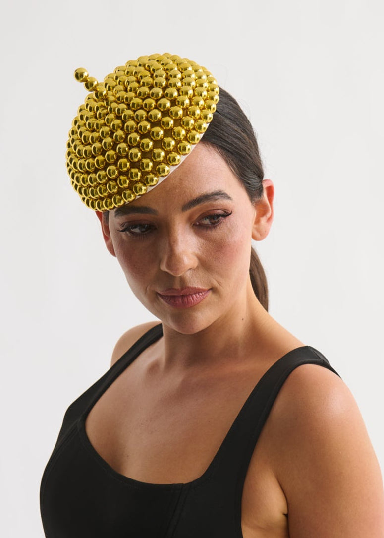 Woman wearing a black dress and gold beaded hat against a white background