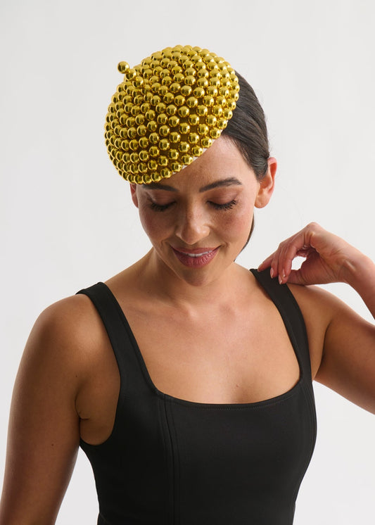 Woman wearing a black dress and a gold beaded hat on a white background