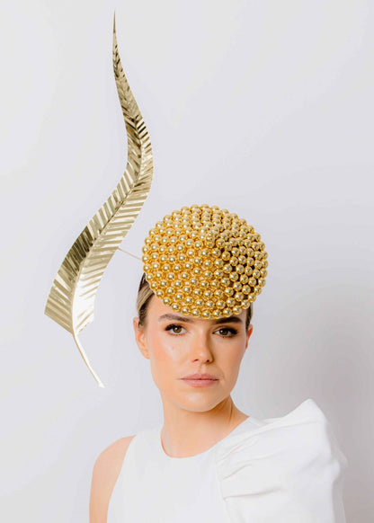 Woman wearing a gold headpiece with a white dress against a plain background