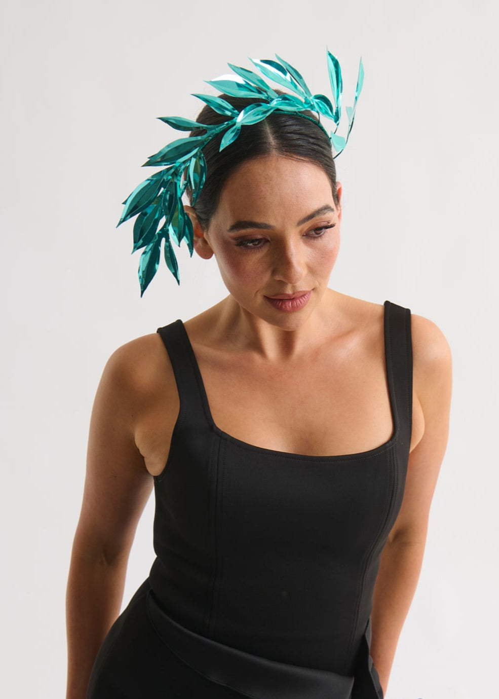 Woman wearing a leaf headpiece and black dress with a white background