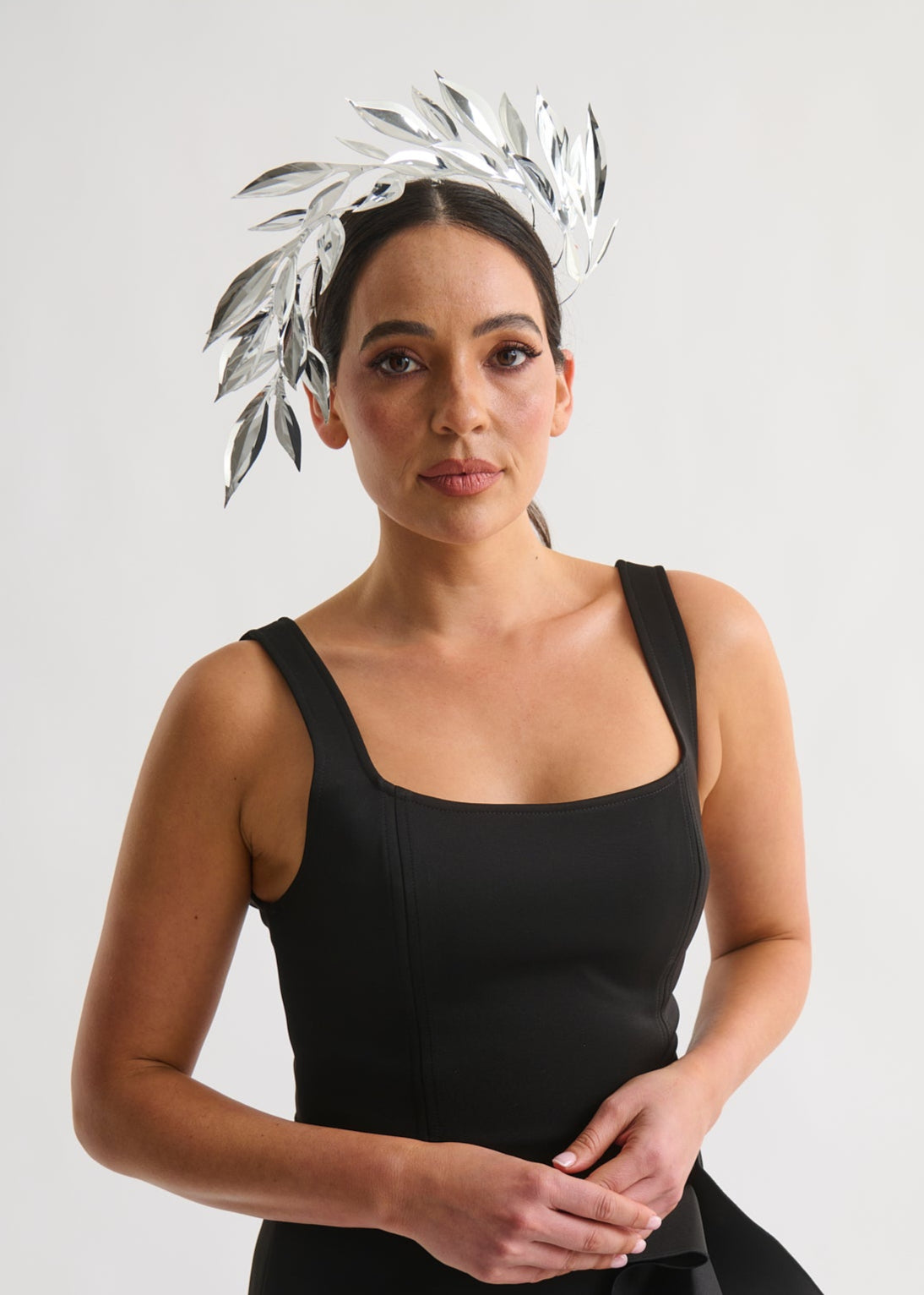Woman wearing a silver leaf headpiece and black dress with a white background