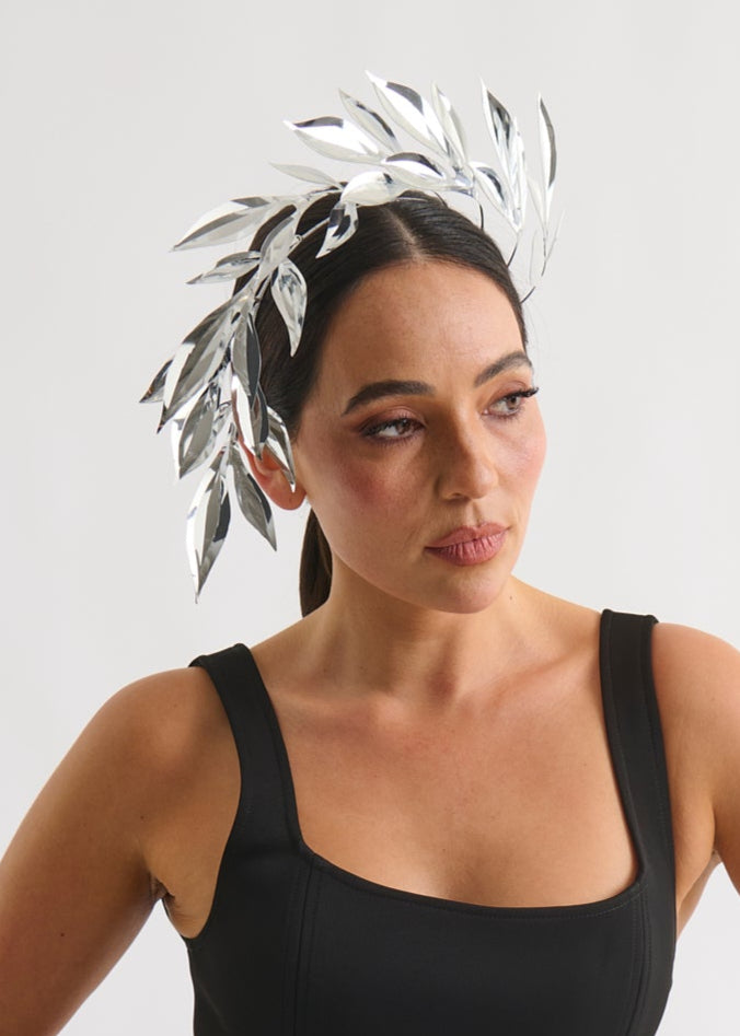 Woman wearing a silver leaf headpiece and black dress with a white background