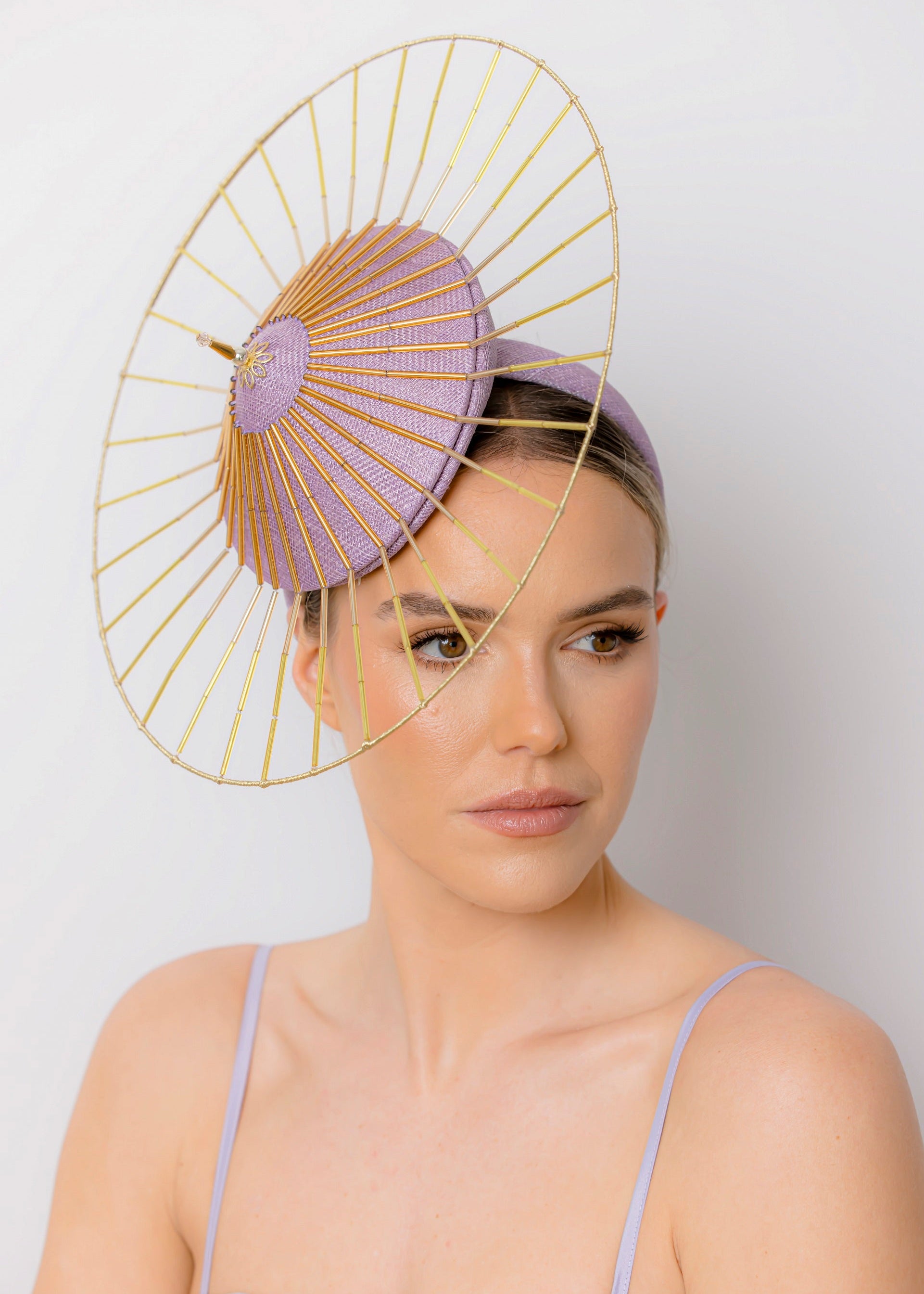 Woman wearing a decorative headpiece with a gold frame and purple accents on a white background