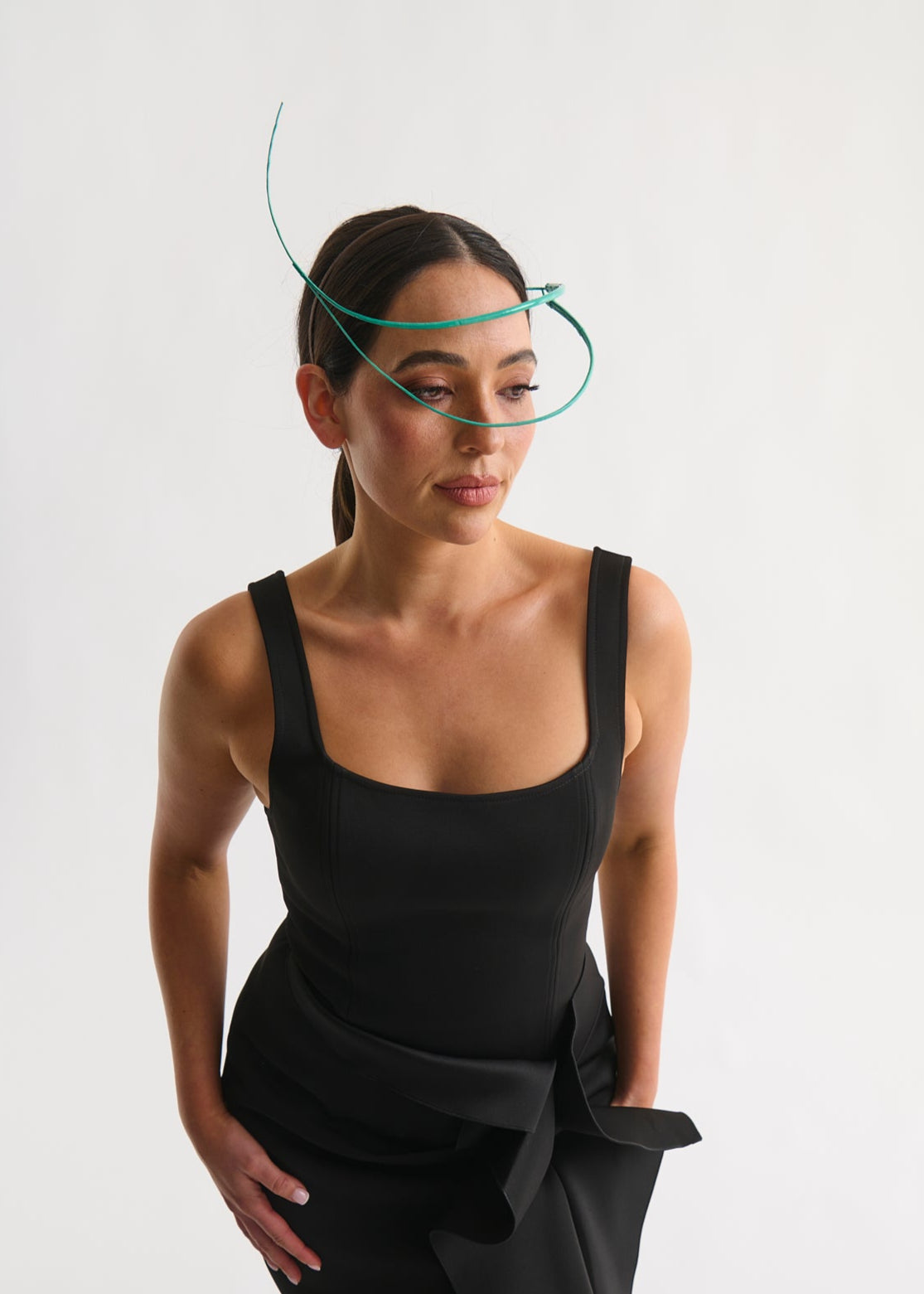 Woman wearing a feather quill headpiece and a black dress against a white background