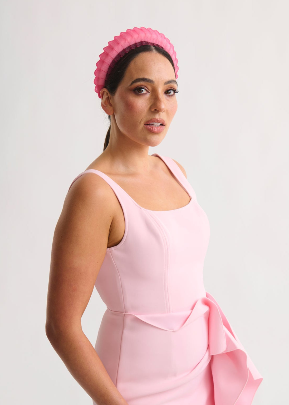 Woman wearing a pink dress and headband against a white background