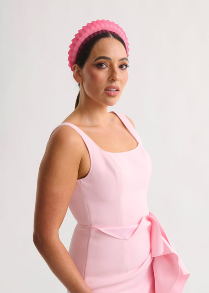 Woman wearing a pink dress and headband against a white background