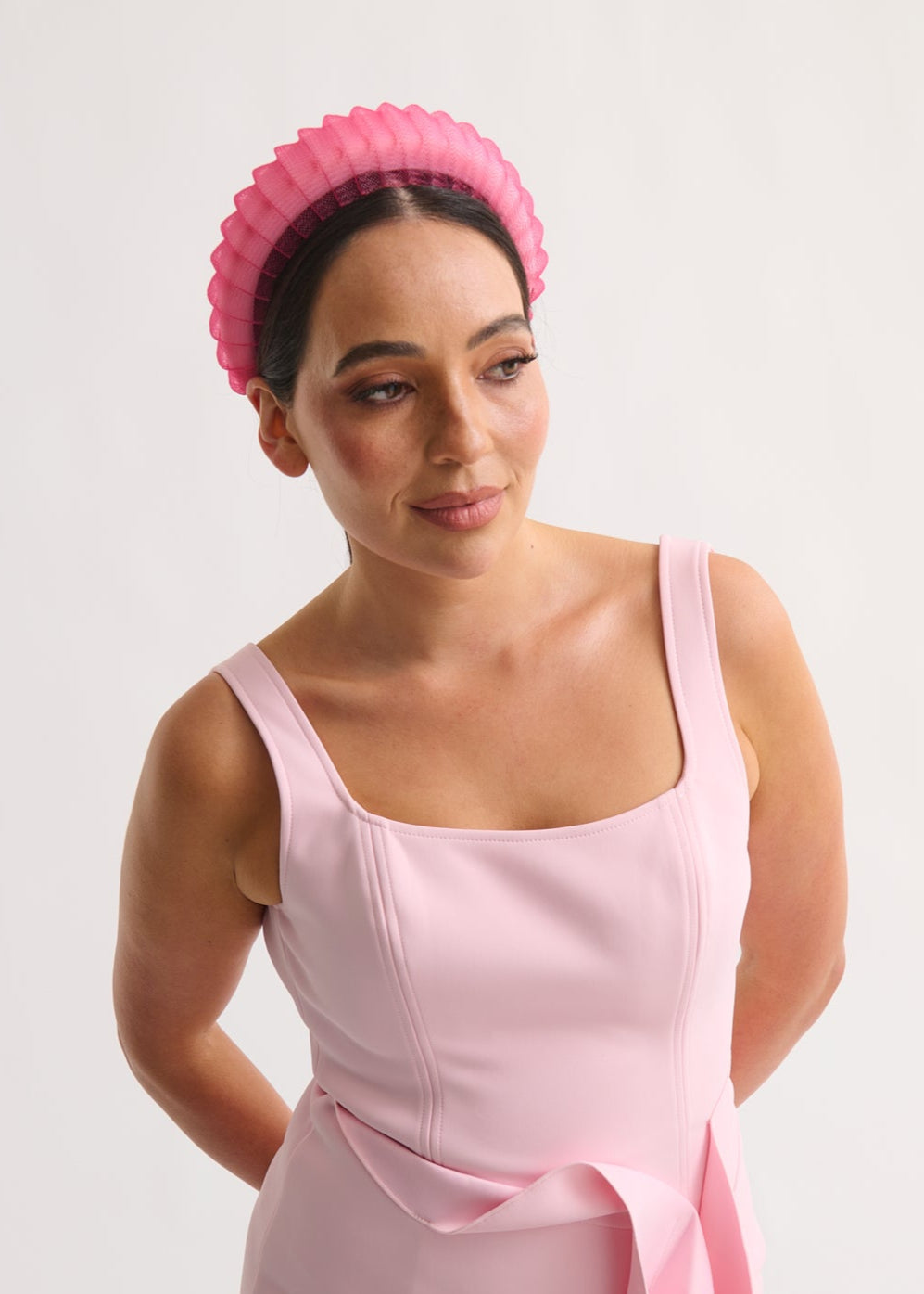 Woman wearing a pink headband and dress against a white background