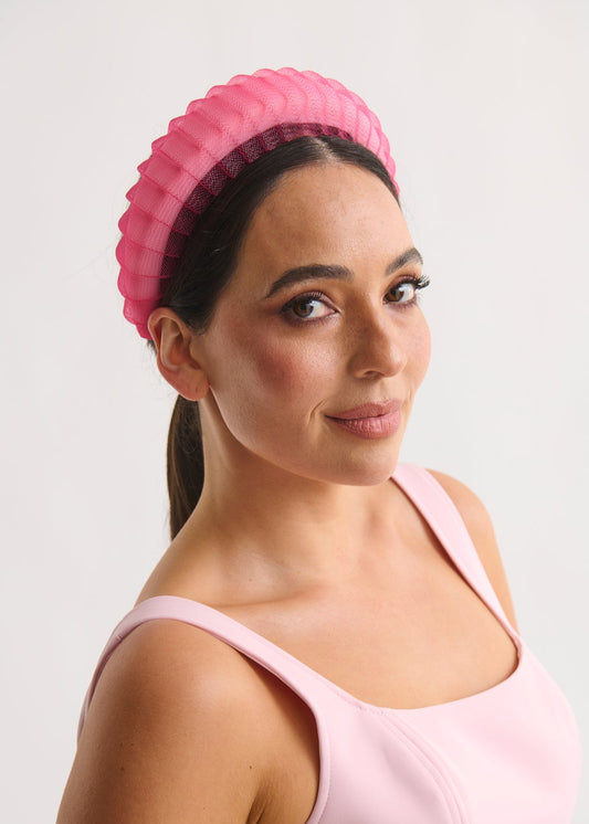 Woman wearing a pink headband against a white background