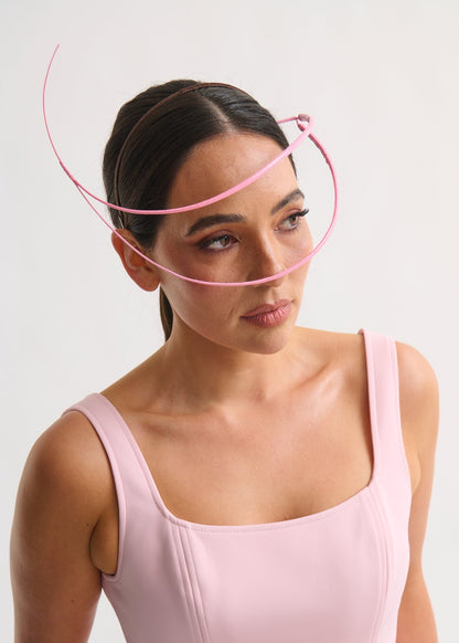 Woman wearing a headpiece and a pink dress against a white background