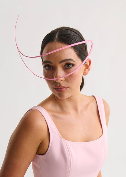 Woman wearing a headpiece and a pink dress against a white background