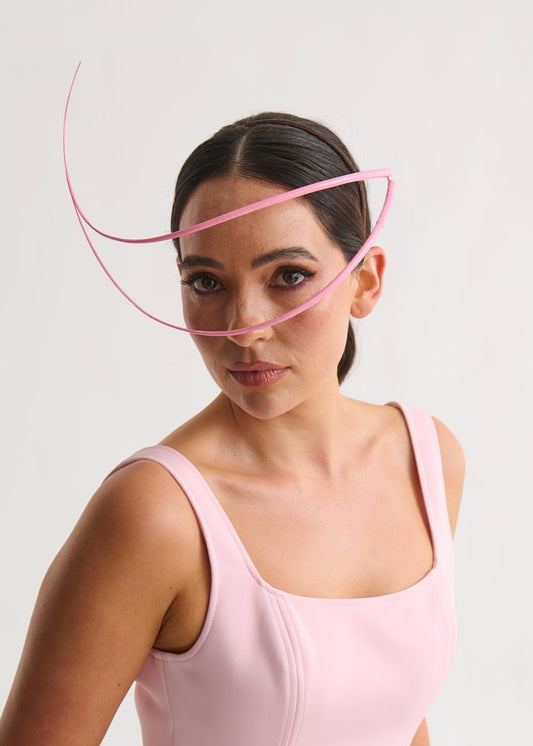 Woman wearing a headpiece and a pink dress against a white background