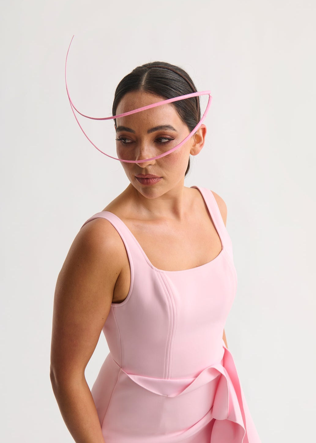 Woman wearing a headpiece and a pink dress against a white background