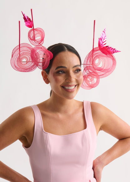 Woman wearing a pink dress with decorative pink elements on a white background