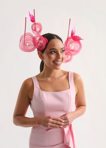 Woman wearing a pink dress with a decorative headpiece on a white background