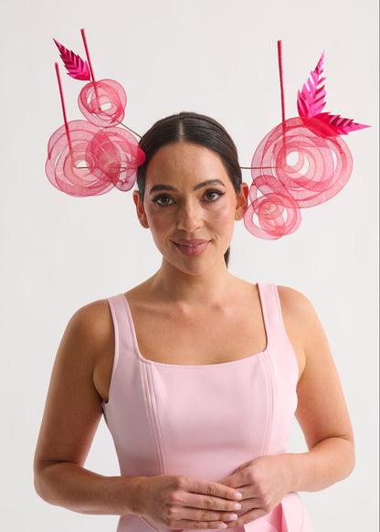 Woman wearing a pink dress with decorative headpiece against a white background