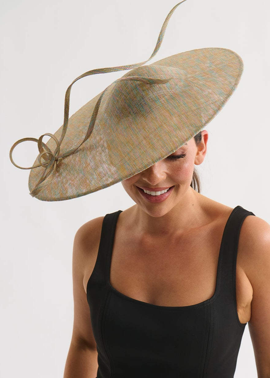 Woman wearing a large decorative hat with a plain background