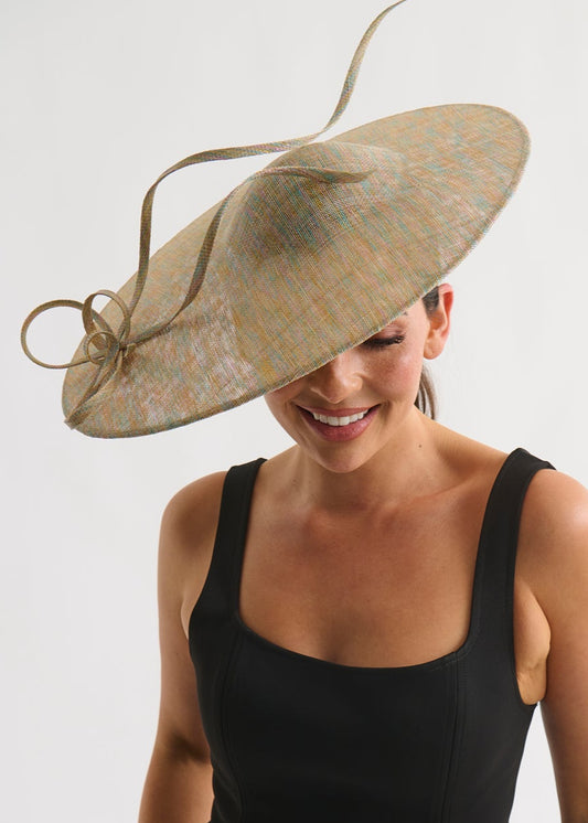 Woman wearing a large decorative hat with a plain background