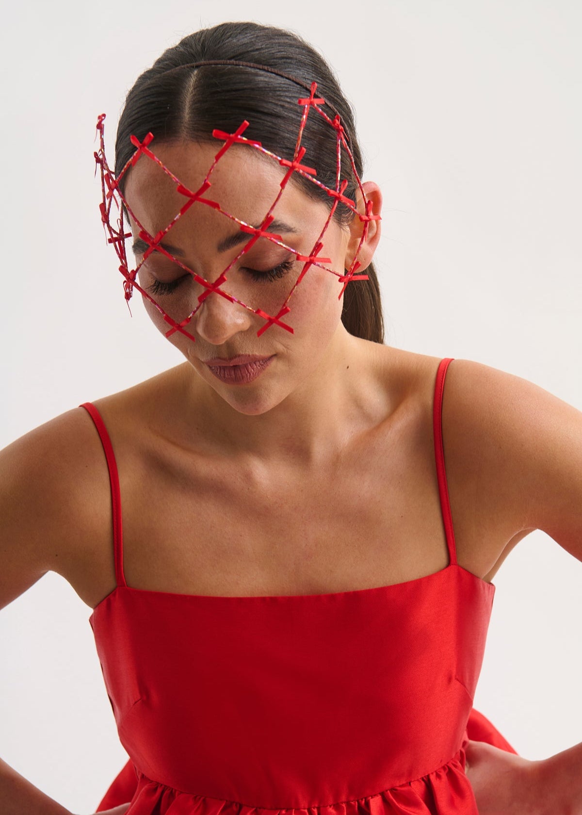 Woman wearing a red dress and headpiece against a white background