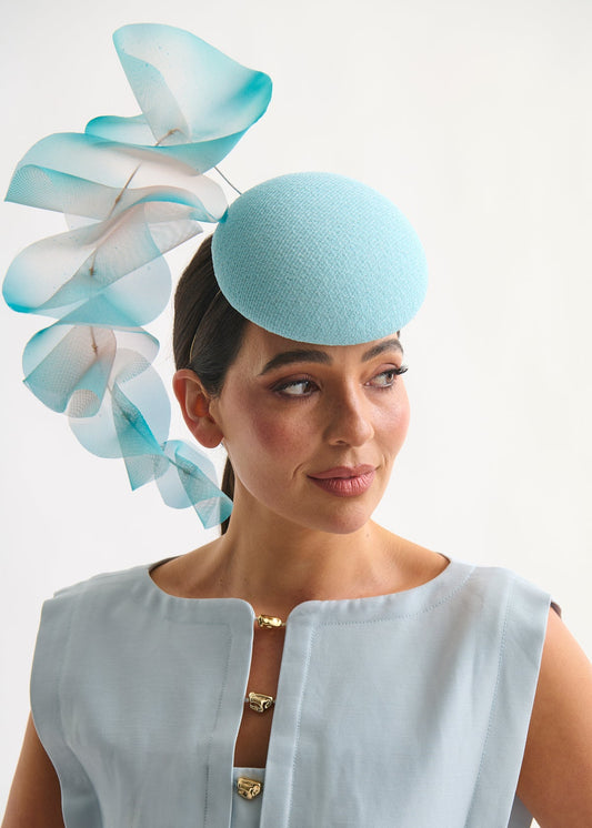 Woman wearing a light blue hat with decorative elements on a white background