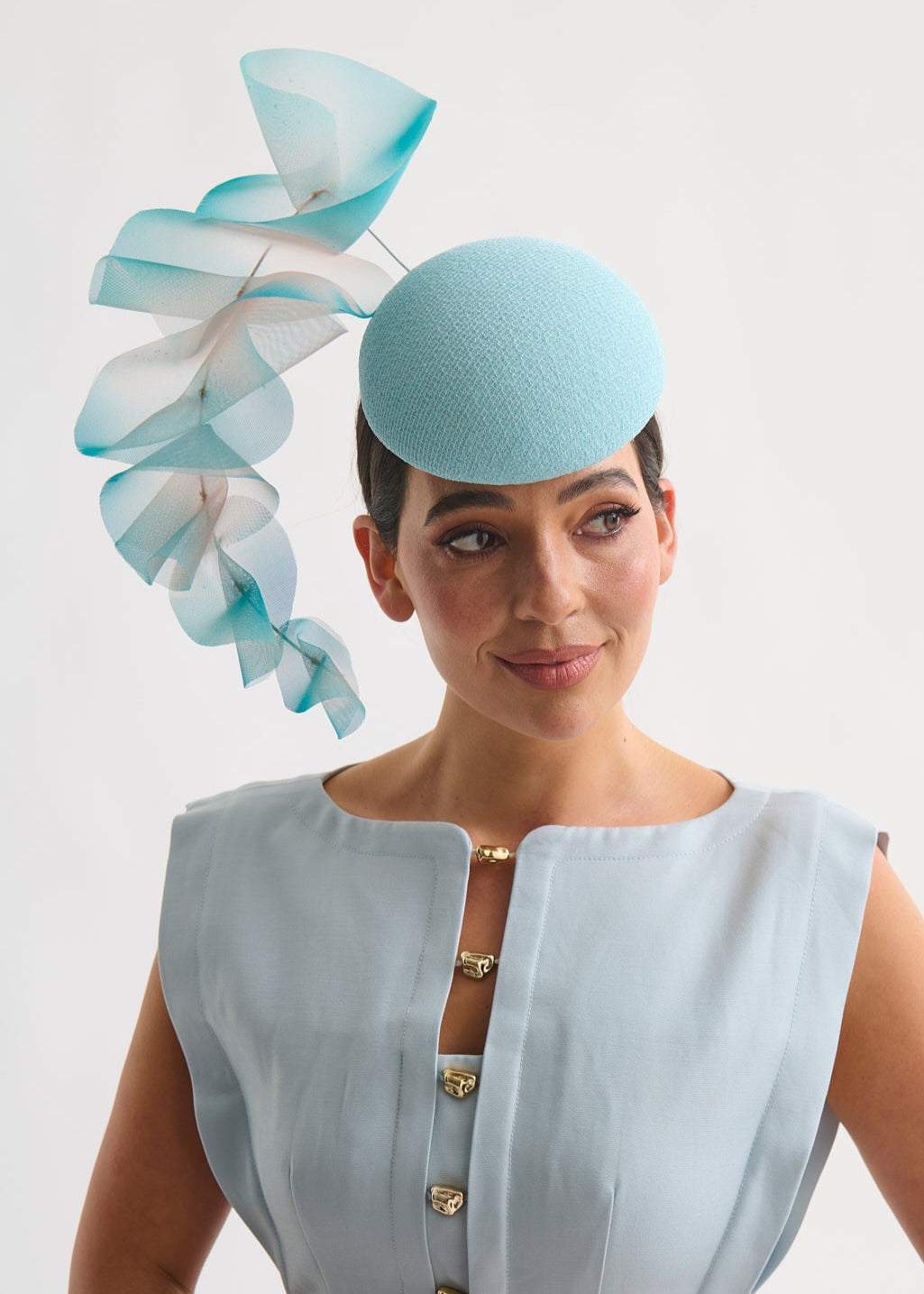 Woman wearing a light blue hat with decorative ruffles on a white background