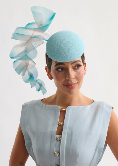 Woman wearing a light blue hat with decorative ruffles on a white background