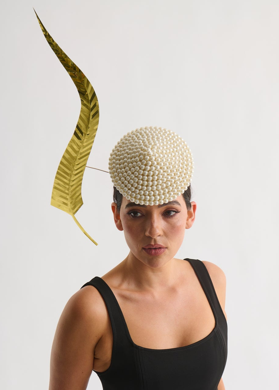 Woman wearing a decorative headpiece with a feather on a plain background