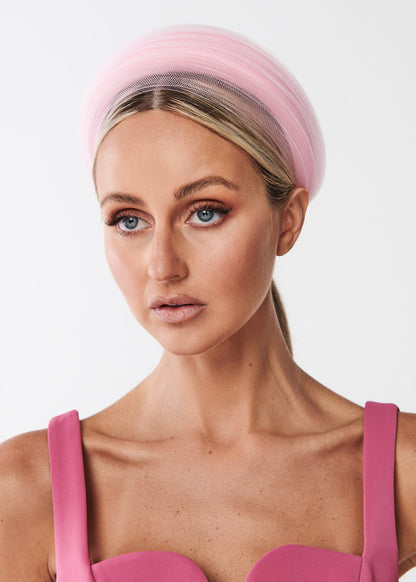 Woman wearing a pink headband and dress against a white background