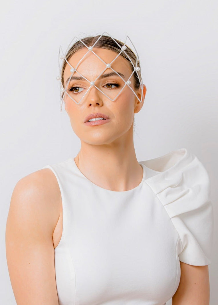 Woman wearing a white dress with ruffled sleeves against a light gray background