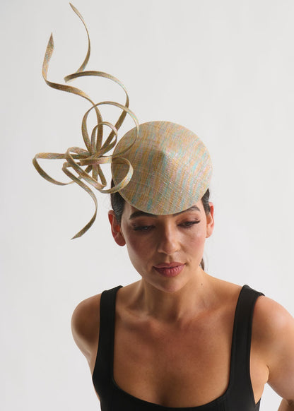 Woman wearing a decorative hat with intricate design on a plain background