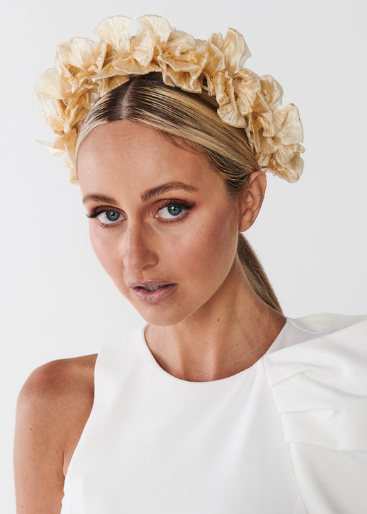 Woman wearing a white dress with a decorative headband on a plain background