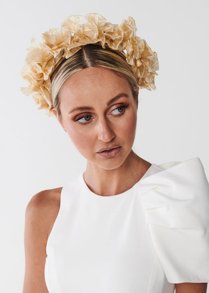Woman wearing a white dress with a decorative headband against a plain background
