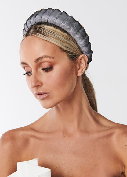 Woman wearing a black padded headband and white dress with a white background